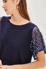 Remera de corte recto y largo cropped, color azul marino, con mangas cortas de encaje bordado con lentejuelas azules brillantes.