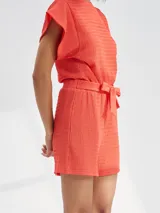 Short de tiro alto con textura arrugada, cuenta con cintura elástica y un lazo decorativo para anudar al frente.