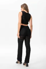Pantalón de hilo negro con cintura elastizada y transparencias sutiles en las piernas.
