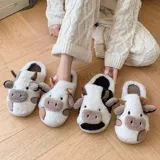 Pantuflas de peluche con diseño de vaca, confeccionadas en piel sintética suave. Cuentan con suela de goma antideslizante y diseño abierto en el talón.