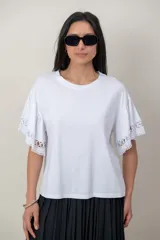 Remera de algodón color blanco, con cuello redondo y mangas cortas holgadas que presentan detalles de encaje broderie.