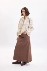 Falda larga de jean color marrón con diseño de paneles y corte evasé.