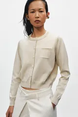 Chaqueta de punto efecto doble capa color beige, con cuello redondo, manga larga y cierre frontal con botones. Cuenta con un bolsillo de plastrón en el pecho y bajo acabado en rib.