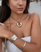 Collar tipo choker con cordón de algodón negro y dije central de metal con forma orgánica irregular y acabado brillante.