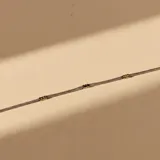 Pulsera de cadena fina tipo tejido con pequeños detalles cilíndricos en oro intercalados a lo largo de la pieza.