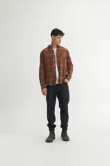 Camisa de franela a cuadros marrones y verdes, corte regular fit, confeccionada en algodón. Tiene cuello solapa clásico, bolsillo en el pecho y botones personalizados.