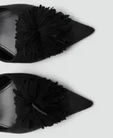 Zapato tipo kitten heel color negro, con punta fina y detalle de pompones en el empeine. Cuenta con una tira ajustable con hebilla en el tobillo.
