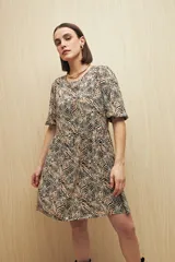 Vestido corto con estampado animal print en tonos beige, negro y marrón. Tiene corte holgado, mangas cortas y falda con vuelo.