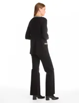 Cardigan de tejido acanalado en color negro, con diseño abierto y manga larga. Presenta detalles de ribete con patrón geométrico en contraste a lo largo de la apertura frontal, en los puños y en los bolsillos simulados.