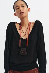 Pack de dos collares de diseño artesanal. El primero presenta una cinta de satén color terracota con flecos, adornada con cuentas negras y un colgante central de madera oscura con una pieza de resina incrustada. El segundo es un collar doble compuesto por una cadena metálica fina y un cordón negro, decorado con cuentas de piedra natural en tonos rojos, marrones y piezas metálicas doradas.