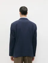 Blazer de medio forro azul marino confeccionado en mezcla de algodón y lino, con silueta estructurada, solapas de muesca, cierre frontal de dos botones y bolsillos con solapa.