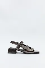 Sandalia con taco medio color peltre y diseño de múltiples tiras con hebillas metálicas ajustables. Su textura símil reptil aporta un aire sofisticado y moderno, mientras que la base ancha brinda estabilidad y confort.