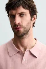 Polo de punto canalé color rosado, de corte regular fit, con cuello solapa y cierre frontal de botonadura. Manga corta y acabados en rib.