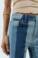 Jeans de tiro medio y pernera recta con diseño de rayas verticales en diferentes tonos de denim. Cuenta con cinco bolsillos y cierre frontal con cremallera y botón.