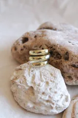 Anillo dorado de bronce con diseño de espiral de tres vueltas.