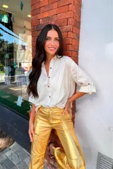 Pantalón dorado de corte acampanado con aberturas laterales en el ruedo.