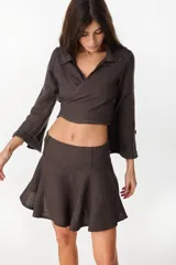 Minifalda color marrón oscuro, confeccionada en lino italiano, con diseño de cintura baja con caderín y bajo acampanado. Cierre invisible en el lateral.