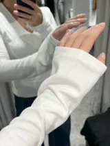 Remera de manga larga color negro, con escote en V y mangas acampanadas tipo Oxford. Confeccionada en tejido de algodón elastizado, con un diseño entallado al cuerpo.
