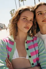 Chaqueta de punto a rayas horizontales en tonos rosado, celeste y verde claro, con cuello polo, manga larga y cierre frontal de botones negros.