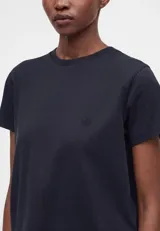 Remera blanca de algodón con corte boxy, ligeramente oversize, de líneas rectas y mangas cortas, con cuello redondo acanalado.
