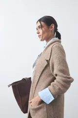 Cardigan de tejido de punto gris, con silueta larga, frente abierto, solapas clásicas y bolsillos aplicados en los laterales.