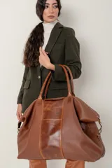 Bolso grande de cuero vacuno color marrón, con cierre superior, doble asa de mano y correa bandolera regulable y desmontable.