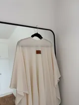 Ruana de tejido fino en color blanco, con diseño abierto y caída fluida, ideal para capas ligeras.