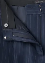 Pantalón de traje tiro medio, corte recto y largo, con diseño de raya diplomática, pinzas y bolsillos laterales.