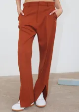 Pantalón de corte recto confeccionado en tela sastrera color ladrillo, con tajo lateral en la botamanga y bolsillos laterales.