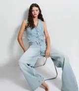 Pantalón de jeans de tiro medio, corte wide leg, color celeste claro desgastado. Presenta un diseño de cintura con cruce frontal y cierre tradicional.
