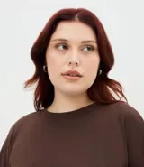Blusa de Ashua confeccionada en tejido rib, color marrón, con cuello redondo y mangas largas. Presenta un diseño de corte holgado y cómodo.