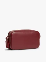 Cartera bandolera Tommy Hilfiger modelo Essential de color bordó, con acabado liso, cierre de cremallera y correa ajustable de jacquard. Presenta el logo y la inscripción de la marca en bajo relieve en la parte delantera.
