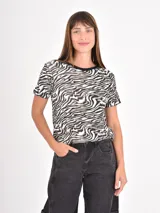 Remera de manga corta con cuello redondo y estampado de líneas onduladas en tonos blanco, negro y beige.
