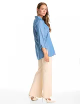 Blusa de lyocell color azul claro, con cuello camisero, escote en V y cierre frontal parcial con botones. Presenta mangas tres cuartos amplias y un corte holgado con aberturas laterales en el ruedo.