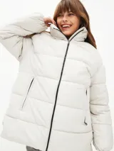 Campera puffer color blanco hueso, con cuello alto, cierre frontal con cremallera y bolsillos laterales con cierre.