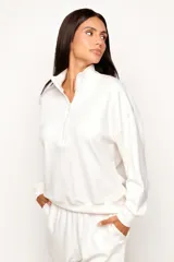 Buzo de viscosa color blanco marfil con cuello alto y cierre frontal parcial, de manga larga y diseño levemente oversize.