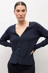 Cardigan negro con escote en V, manga larga y cierre frontal con botones pequeños. Presenta puños acanalados con detalle de botones decorativos.
