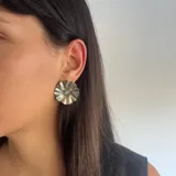 Aros tipo caravana plateados con forma de flor y circonita transparente en el centro.