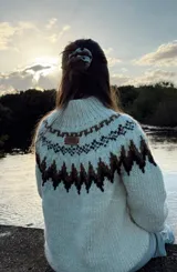 Sweater tejido a mano en lana merino color crudo con diseño geométrico en marrón y cuello alto.