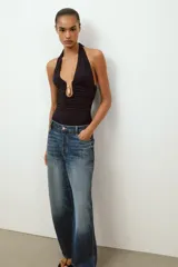 Body de cuello halter con espalda descubierta, confeccionado en poliamida. Presenta un diseño drapeado en los laterales y una abertura frontal con detalle metálico. Posee cierre con botones a presión en la parte inferior y lazada en el cuello.