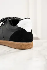 Zapatillas urbanas de cuero negro con puntera y talón de gamuza negra, detalles en cuero con textura de reptil y suela de goma color caramelo.