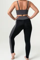 Calza deportiva de tiro alto con cintura elástica reforzada. Presenta un diseño bicolor que combina paneles laterales y faja con estampado animal print en tonos coral y turquesa sobre una base negra.