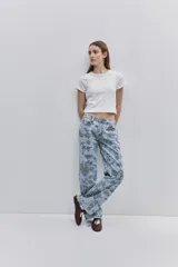 Jean de tiro medio con calce amplio y piernas wide leg, confeccionado en denim celeste con estampado floral. Cuenta con diseño de cinco bolsillos y cierre frontal con botón y cremallera.