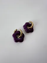Aros de acero quirúrgico hipoalergénico con argolla dorada y dije colgante en forma de flor color violeta.
