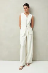 Pantalón sastrero ancho color crema con finas rayas verticales, de cintura alta con pinzas.