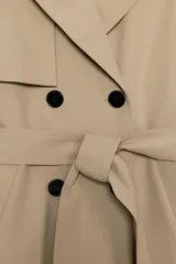 Trench largo de color negro con cuello de solapa, manga larga con trabillas ajustables y cierre frontal cruzado con doble botonadura. Cuenta con bolsillos delanteros de vivo, solapa cortavientos en el pecho y cinturón ajustable del mismo tejido.