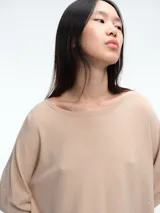 Sweater de punto amplio con sutiles micro lentejuelas integradas al tejido. Presenta cuello redondo relajado, hombros caídos y mangas largas con puños ajustados. Su diseño cuenta con un largo generoso y aberturas laterales en el ruedo.