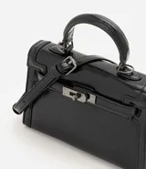 Cartera bandolera Satinato pequeña, de estructura rígida y diseño rectangular, confeccionada en PU negro con acabado levemente brillante. Cuenta con cierre frontal metálico con traba, asa de mano superior y correa larga removible y ajustable.