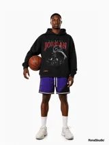 Hoodie negro de corte amplio con estampa frontal de Michael Jordan en acción y letras en color rojo. Cuenta con capucha con cordones ajustables, bolsillo tipo canguro y puños acanalados.