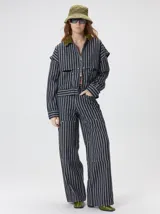 Campera de denim a rayas verticales con cuello de pana en color bordó. Presenta cierre frontal, mangas desmontables con cierre en los hombros, canesú en el pecho y bolsillos de parche cuadrados.